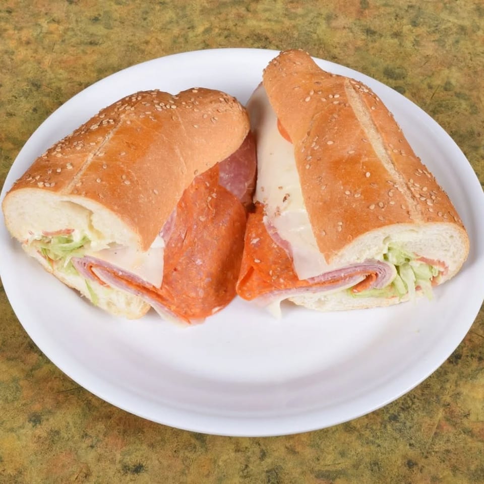 Two halves of a Midways De La Roma Italian sub sandwich with meats, cheese, and lettuce.